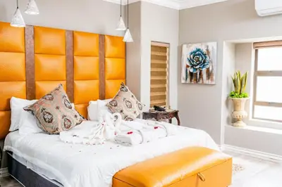 a bedroom with a large bed with an orange headboard at Re-Union Vacations in Hartbeespoort