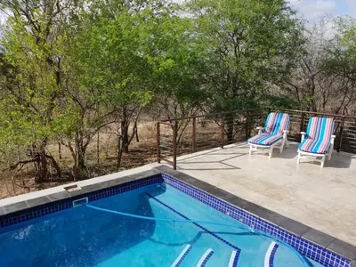 a swimming pool with two chairs sitting next to it at Lionsview Private Lodge - 6 Lions in Marloth Park
