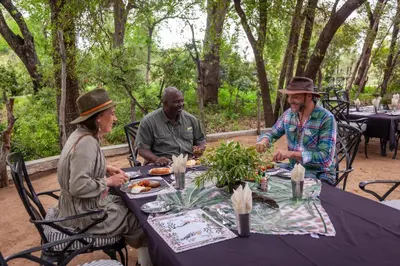 three people sitting at a table eating food at Kings Camp in Timbavati Game Reserve
