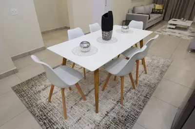 a white dining room table with white chairs on a rug at Elridge Living in Boksburg