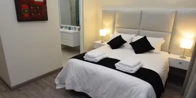 a bedroom with a large white bed with two lamps at Elridge Living in Boksburg