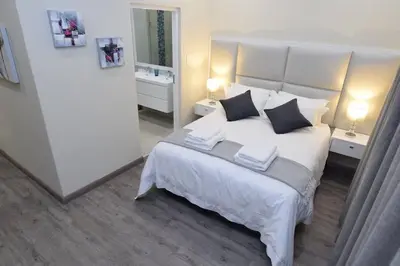 a bedroom with a large white bed with two night stands at Elridge Living in Boksburg
