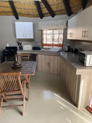 a kitchen with wooden cabinets and a wooden table and chairs at Jock of the Bushveld in Barberton