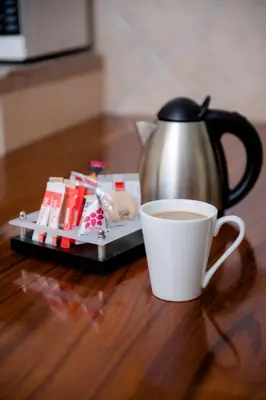 a coffee pot and a cup of coffee on a table at Palm Park Hotel in Ellisras