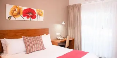 a bedroom with a bed and a desk with a phone at Palm Park Hotel in Ellisras