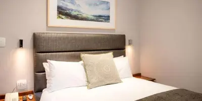 a bedroom with a white bed with a large headboard at Palm Park Hotel in Ellisras
