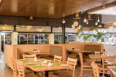 a restaurant with wooden tables and chairs and windows at Palm Park Hotel in Ellisras