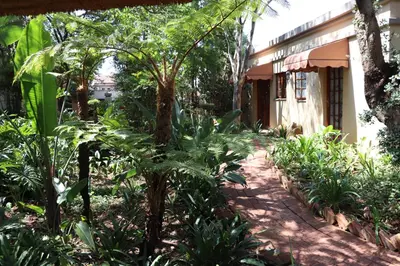 a garden with trees and plants next to a building at Greenwoods Self-Catering in Pretoria