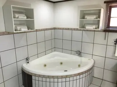 a bath tub in a white tiled bathroom at Greenwoods Self-Catering in Pretoria