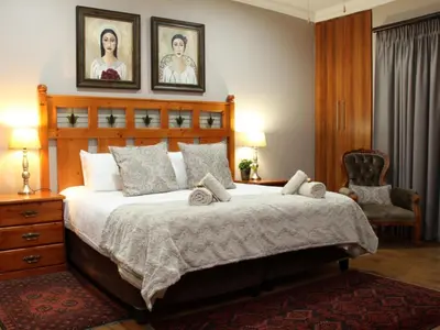 a bedroom with a large bed with two pictures on the wall at Feathers Guest House in Middelburg