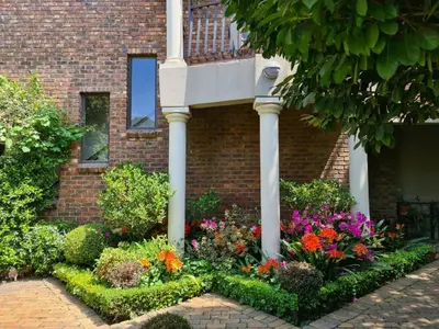 a garden of flowers in front of a brick building at Feathers Guest House in Middelburg