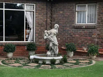 a statue of a woman in front of a brick building at Feathers Guest House in Middelburg