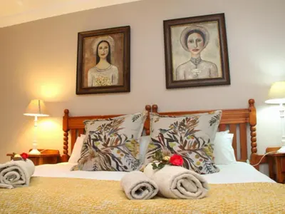 a bedroom with a bed with two pictures on the wall at Feathers Guest House in Middelburg