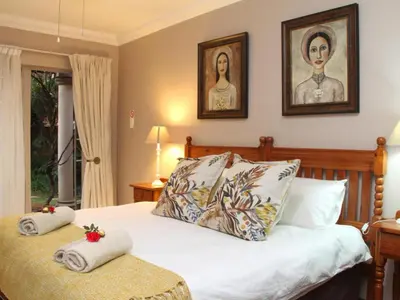 a bedroom with a bed with two pictures on the wall at Feathers Guest House in Middelburg