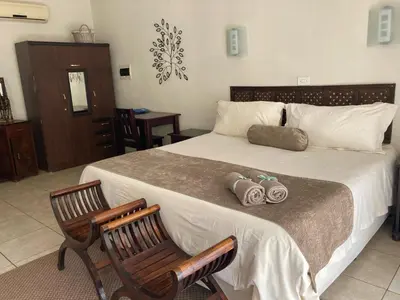 a bedroom with a large bed and two chairs at Acasia Guest Lodge in Komatipoort