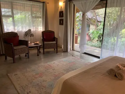 a bedroom with a bed and two chairs and a table at Acasia Guest Lodge in Komatipoort