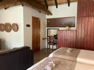 a hotel room with two beds and a dining room at Acasia Guest Lodge in Komatipoort