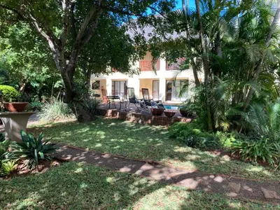 a house with a yard with palm trees and a patio at Acasia Guest Lodge in Komatipoort