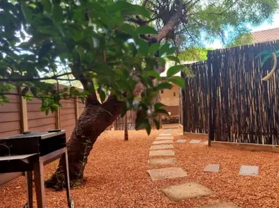 a tree in a yard next to a fence at Palm Inn Guesthouse in Onverwacht