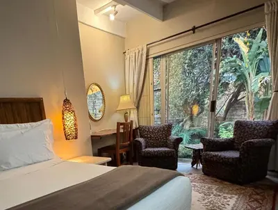 a bedroom with a bed and two chairs and a window at Camellia Haven in Pretoria