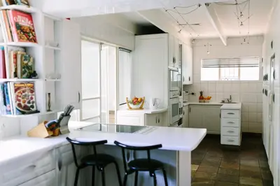 a kitchen with a white counter and stools in it at Camellia Haven in Pretoria