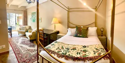 a bedroom with a canopy bed and a living room at Camellia Haven in Pretoria