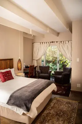 a bedroom with a large bed and a large window at Camellia Haven in Pretoria