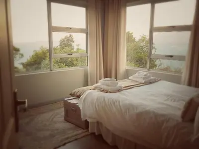 a bedroom with a bed and two windows with towels at Lind End Guest Farm in Haenertsburg