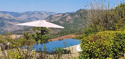 an umbrella next to a pool with mountains in the background at Lind End Guest Farm in Haenertsburg