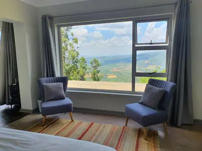 a bedroom with two chairs and a large window at Lind End Guest Farm in Haenertsburg