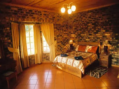 a bedroom with a bed and a brick wall at Thaba Tsweni Lodge & Safaris in Graskop