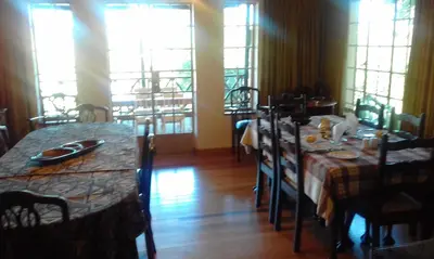 a dining room with a table and chairs and windows at Thaba Tsweni Lodge & Safaris in Graskop