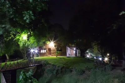 a house with lights in the yard at night at Klippan River Lodge in Groblersbrug