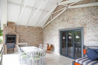 a patio with a table and chairs and a brick wall at Klippan River Lodge in Groblersbrug