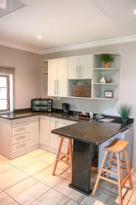 a kitchen with a table and two stools at Klippan River Lodge in Groblersbrug