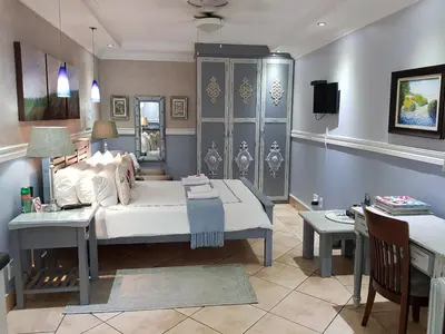 a bedroom with a bed and a table and a desk at Pheasant Hill Bed and Breakfast in Rietvalleirand