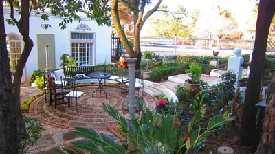 a patio with a table and chairs in a garden at Pheasant Hill Bed and Breakfast in Rietvalleirand