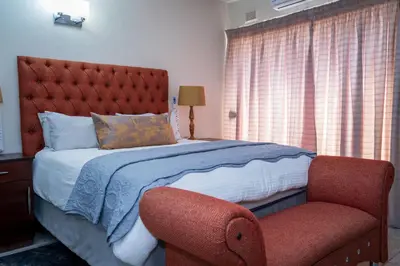 a bedroom with a large bed and a chair at Gaza Homes Self Catering Apartments in Nelspruit
