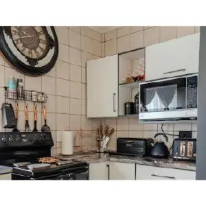 a kitchen with white cabinets and a clock on the wall at Gaza Homes Self Catering Apartments in Nelspruit