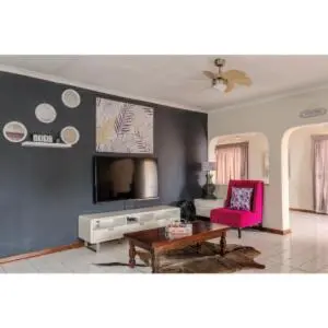 a living room with a pink chair and a tv at Gaza Homes Self Catering Apartments in Nelspruit