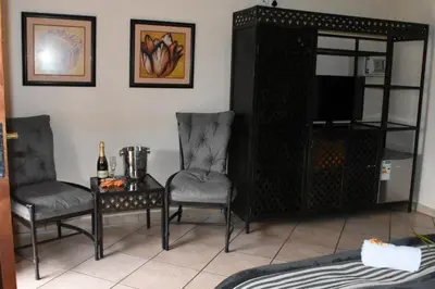 a living room with two chairs and a table and a tv at Batter Boys Guest House in Pretoria
