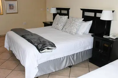 a bedroom with a large bed with white sheets and pillows at Batter Boys Guest House in Pretoria