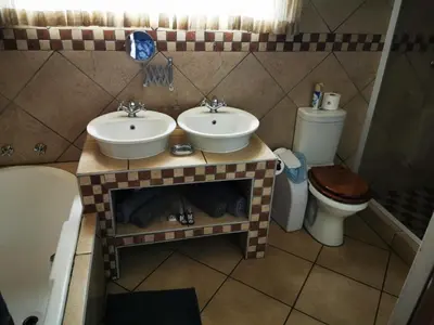 a bathroom with two sinks and a toilet at Batter Boys Guest House in Pretoria