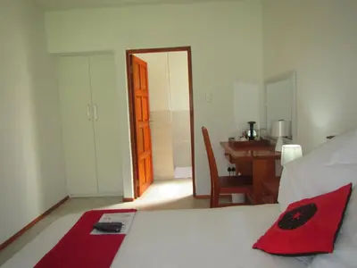 a bedroom with a bed and a table and a desk at African Footprints Lodge in Midrand