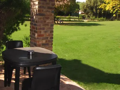a black table with two chairs and a grass field at African Footprints Lodge in Midrand