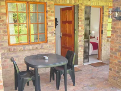 a table and chairs in a room with a door at African Footprints Lodge in Midrand