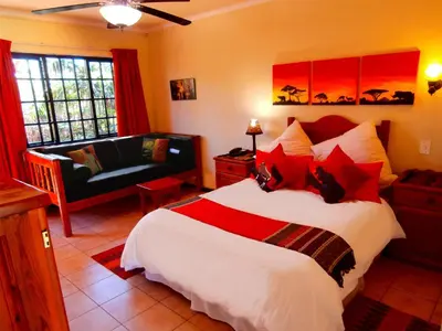 a bedroom with a bed and a living room with a couch at African Footprints Lodge in Midrand