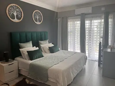 a bedroom with a large bed with a green headboard at KwaSiya Guest House in Nelspruit