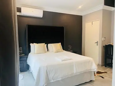 a bedroom with a white bed with a black wall at KwaSiya Guest House in Nelspruit