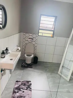 a bathroom with a sink and a toilet and a window at KwaSiya Guest House in Nelspruit